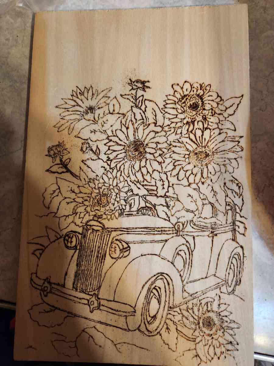 a wood burning of a car and sunflowers hand made