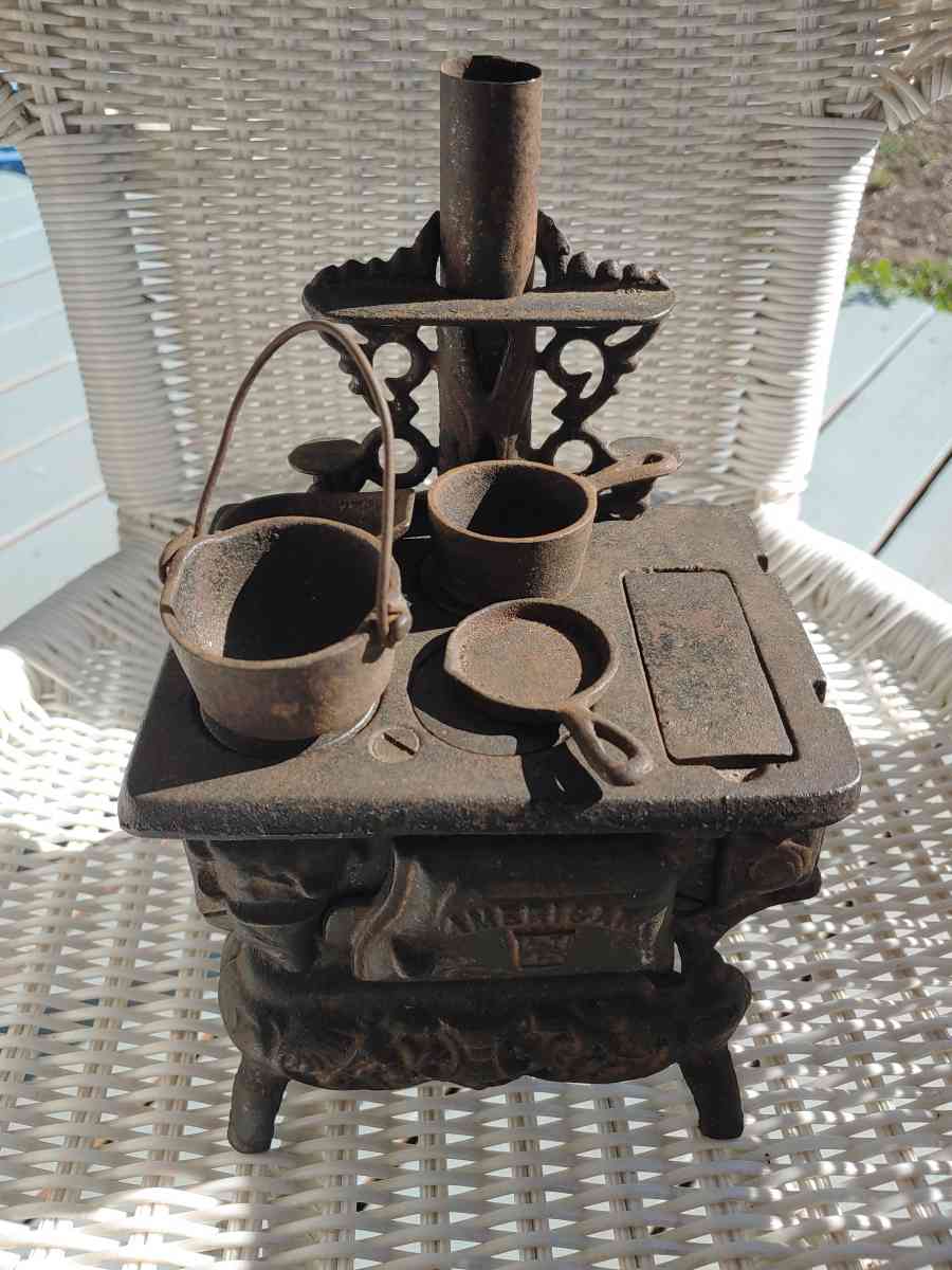 childs iron Play stove with all of the pans and a brass toy
