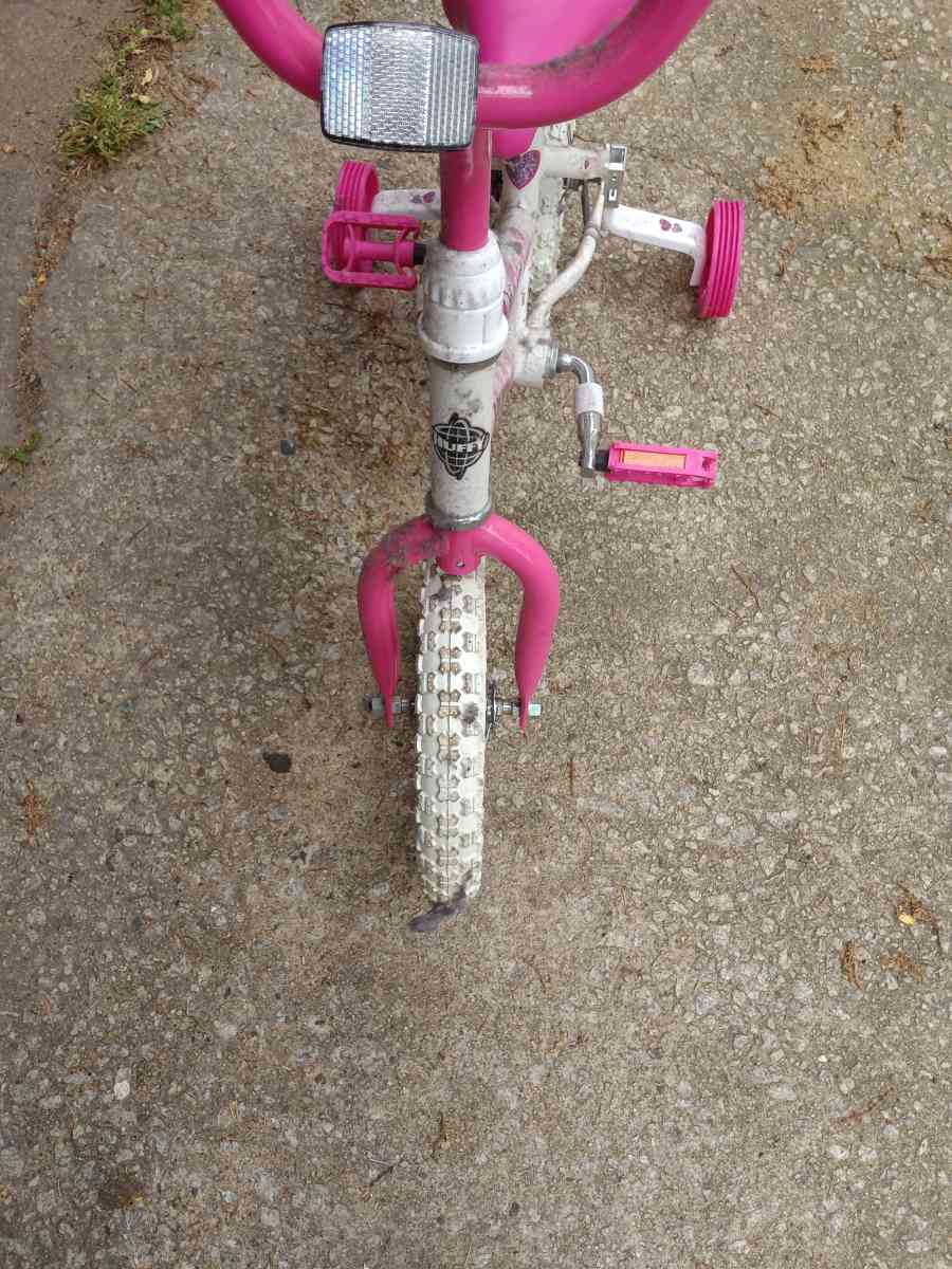 a healthy Barbie pink and white bike with training wheels