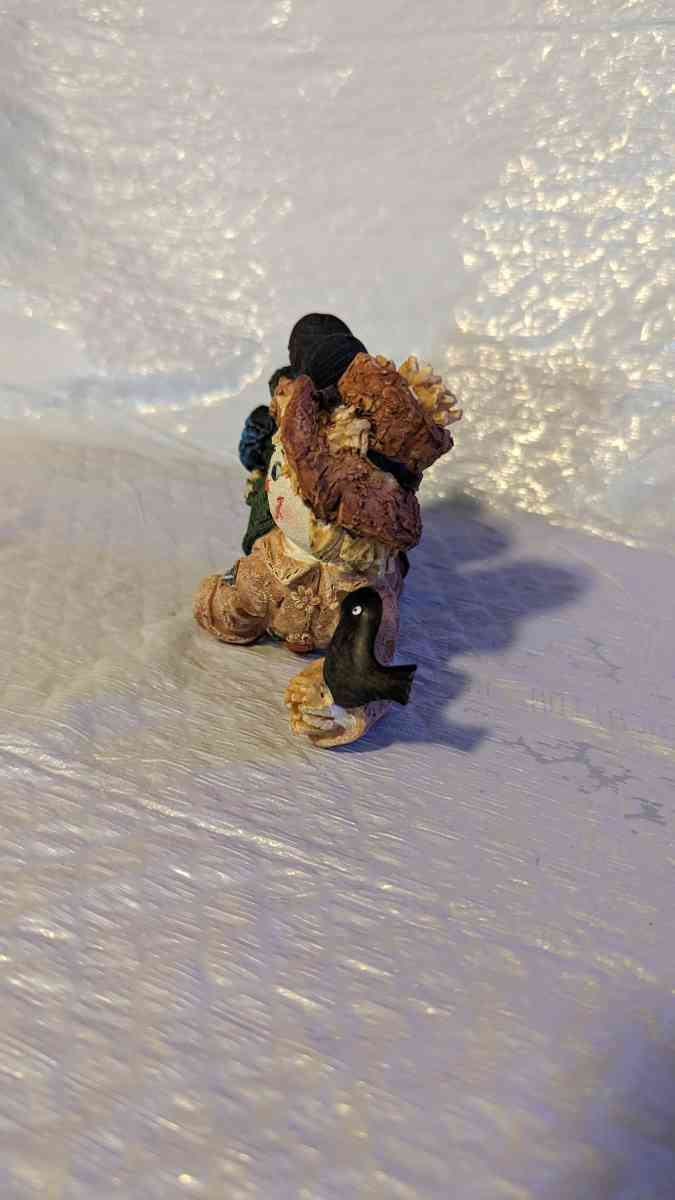 Resin Scarecrow Laying Down With Legs Bent Holding A Crow